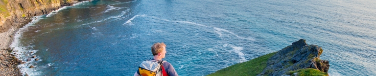 Rear view of man standing on a mountain near the water