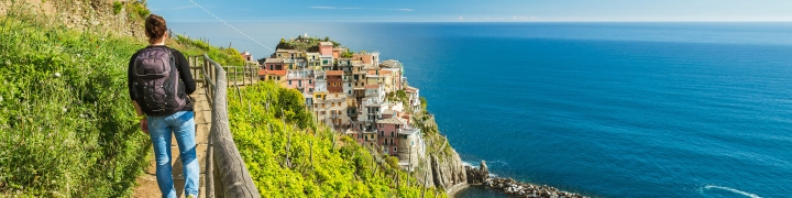 Woman hiking along a path by a vineyard with coastal views in Cinque Terre, Italy