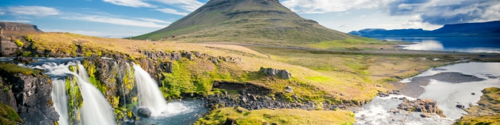 Scenic view of kirkjufell mountain with waterfalls and green fields in Iceland