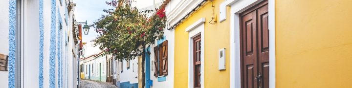 Cobblestone street by brightly colored buildings in Portugal