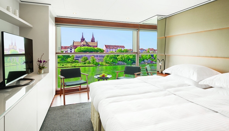 a hotel bedroom with window looking onto a village