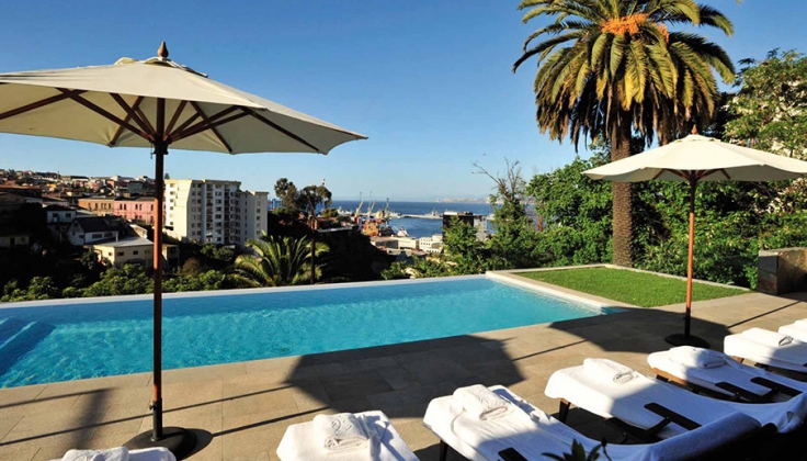 Outdoor pool overlooking city to the port with palm trees