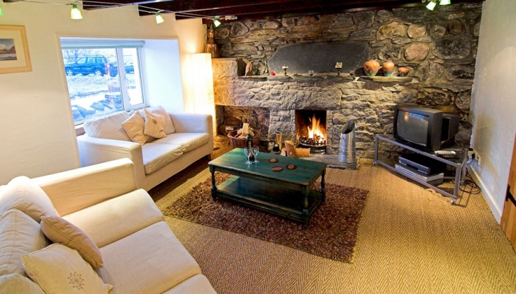 living room with stone fireplace and wooden ceiling beams