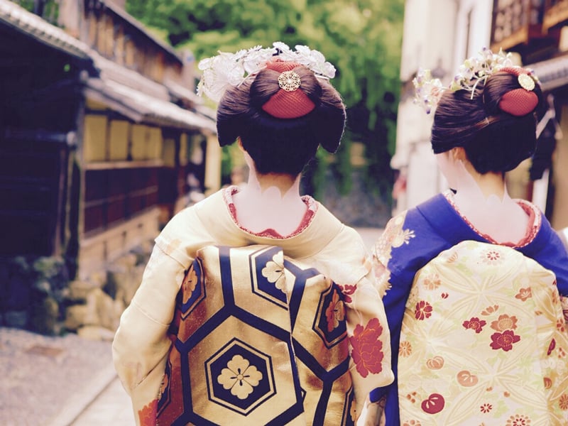 Geishas from Japan walking down a walkway