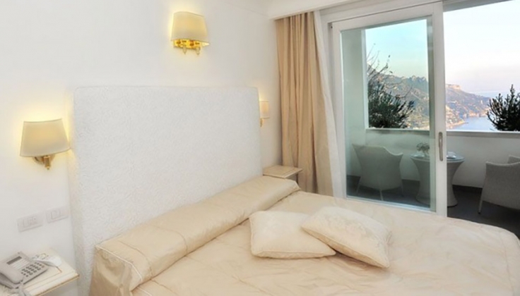 a hotel bedroom with window overlooking ocean