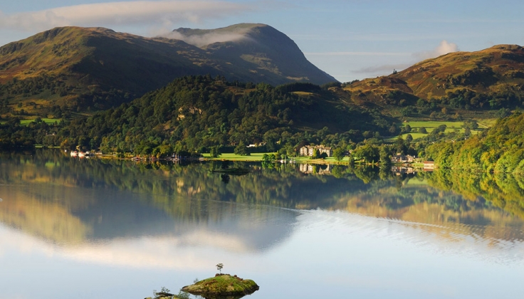 a calm lake with hills and hotel in the background