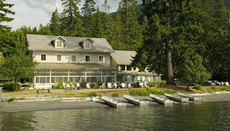 lakefront hotel lodge with trees in background and aluminum boats along the shore